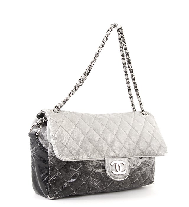 This is an authentic Chanel bag. It is done in a two-toned black and silver textured leather with silver-toned hardware. It features a flap and snap closure, dual leather chain link handles. The interior is done in a coordinating grey/silver and
