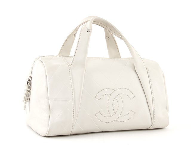 This is an authentic Chanel bag. It is done in ivory leather with silver-toned hardware. It features diagonal and diamond quilted accents, a large stitch quilted CC logo on the exterior front, two flat handles, and a dual zip closure. The roomy