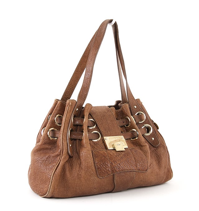 This is an authentic JIMMY CHOO Caramel Embossed Leather Riki Shopper Bag. It is done in soft supple caramel leather with shiny gold hardware. This bag features a pleated double drawstring top and logo-embossed push-lock closure, and two flat