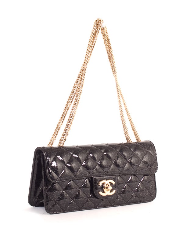 This is an authentic Chanel Black Patent Leather Quilted Flap Bag.  Done in a gorgeous black patent leather, this bag has a subtle glitter speckled throughout the material on the bag. It has gold hardware on the linking bijoux chain strap and the