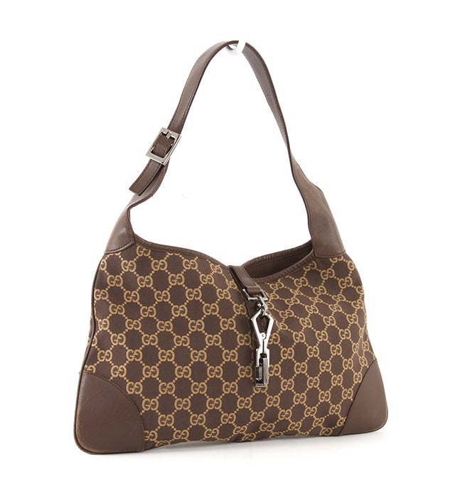 This is an authentic GUCCI Jackie O Hobo Monogram Bag. It is done in brown and gold signature Gucci monogram canvas with brown leather trim and silver-toned hardware. It features a single flat leather shoulder strap and a clasp closure. The interior