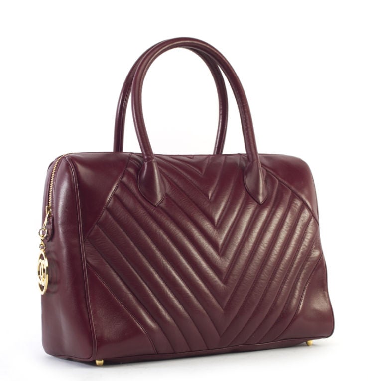 This is an authentic Chanel Burgundy Lamb Chevron Boston Speedy Bag. It is done in smooth, supple burgundy colored lambskin leather with Chevron quilting and elegant gold hardware. It features two comfortable rolled leather handles and a single