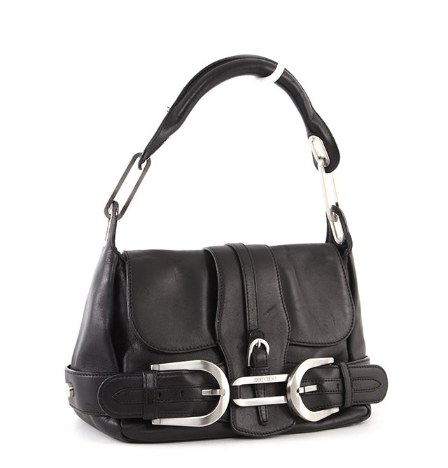 This is an authentic Jimmy Choo bag. It is done in lovely black leather with silver-toned hardware and accents. It features buckle detailing, a single rolled handle, and a flap closure. The interior is done in soft tan suede with black leather trim
