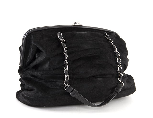 This is an authentic Chanel bag. This unique bag is done in black pony hair and features gunmetal-toned hardware, two leather-chain link handles, and a kiss lock closure. The unique construction of this bag creates lovely wrinkles that lend a plush