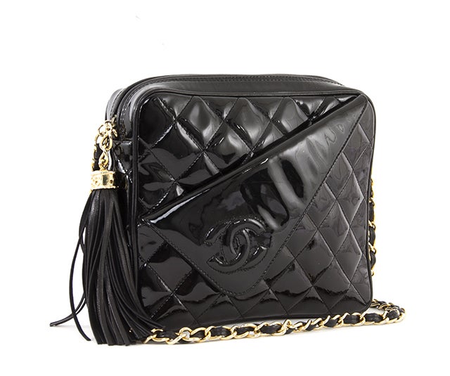 This is an authentic vintage Chanel black patent mini shoulder bag. This compact bag is done in gorgeous black patent quilted leather. The front features a unique diagonal fold-down with the top stitched CC logo. The interior of this bag is done in