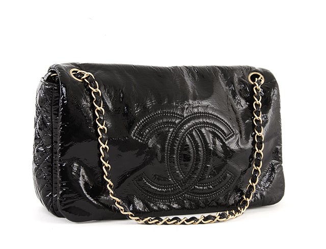 This is an authentic Chanel Patent Rock and Chain shoulder bag. The shiny black exterior is naturally crinkled and features the iconic CC logo top-stitched on the front flap. The gold-toned leather and chain shoulder straps make this bag classic