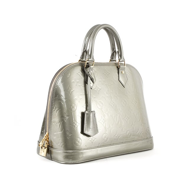 This is an authentic Louis Vuitton Gris Vernis Alma MM bag. It is done in glossy Vernis patent leather with embossed monogram Louis Vuitton logo throughout the body of the bag accented by elegant golden hardware. It features a flat, structured
