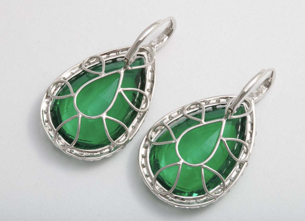 Striking reconstructed green emerald, 40.67 cts, earrings flanked with 76 round diamonds weighing 2.64 carats, in 18 karat white gold.Picture does not do these earrings justice, must see them in person!

 Please note that the emeralds are treated.