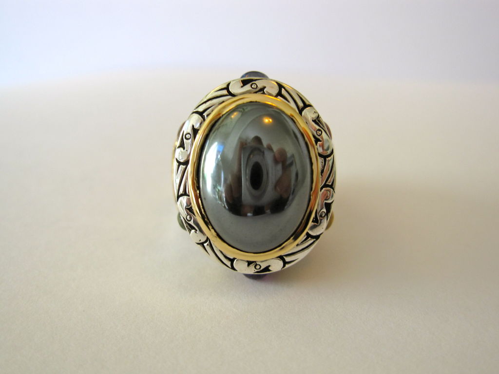 11.10 carat Hematite cabochon (16mm x 12mm) surrounded by 2.7 carats of multi-colored Sapphire cabochons and set with both 18K Yellow Gold and .925 Sterling Silver.
