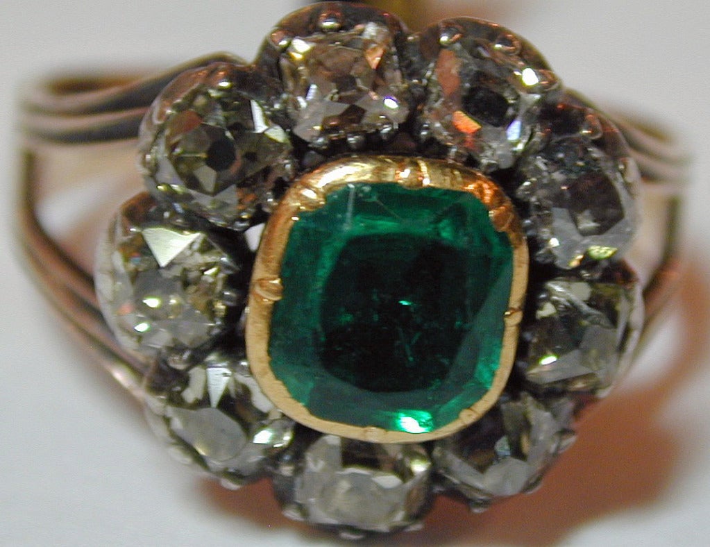 Elegant emerald ring surrounded by nine cushion cut diamonds set in 15K gold and silver. The ring is size 8 3/4 and can be sized to fit.