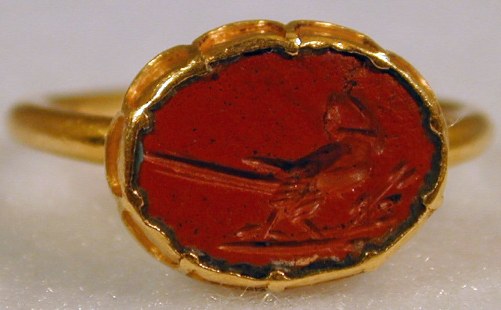 Early intaglio ring of a parrot carved in red jasper in an 18K gold cusped setting with a floral carving at the back of the band.  The ring is size 6 1/2 and can be sized to fit.
