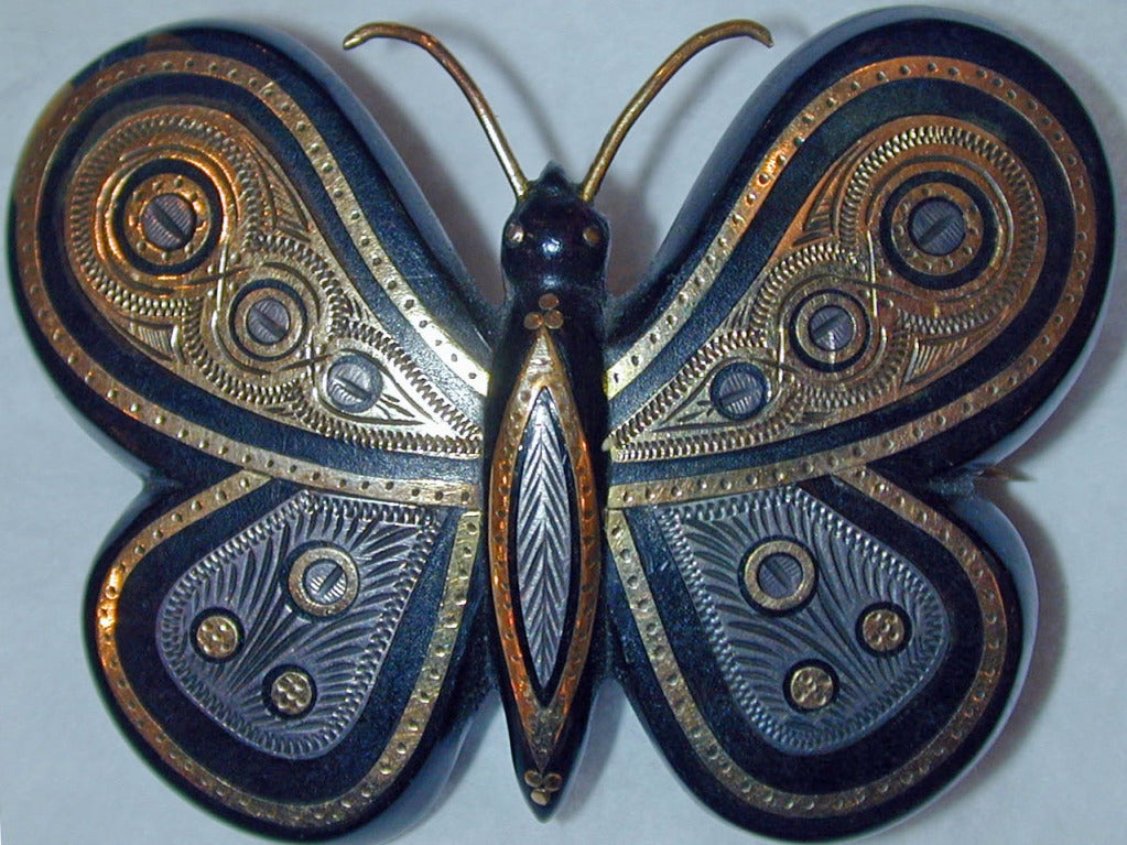 Bold butterfly brooch of pique, tortoiseshell inlaid with gold and silver, will flatter any neckline or shoulder on a suit or on a sweater. Pique was developed in France and became popular in England in the late 19th century.