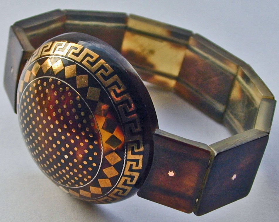 Bold pique expansion bracelet with a large disc inlaid with geometric designs. Pique is tortoiseshell inlaid with gold and silver. The technique was brought to England by Huguenot craftsmen in the 17th century.