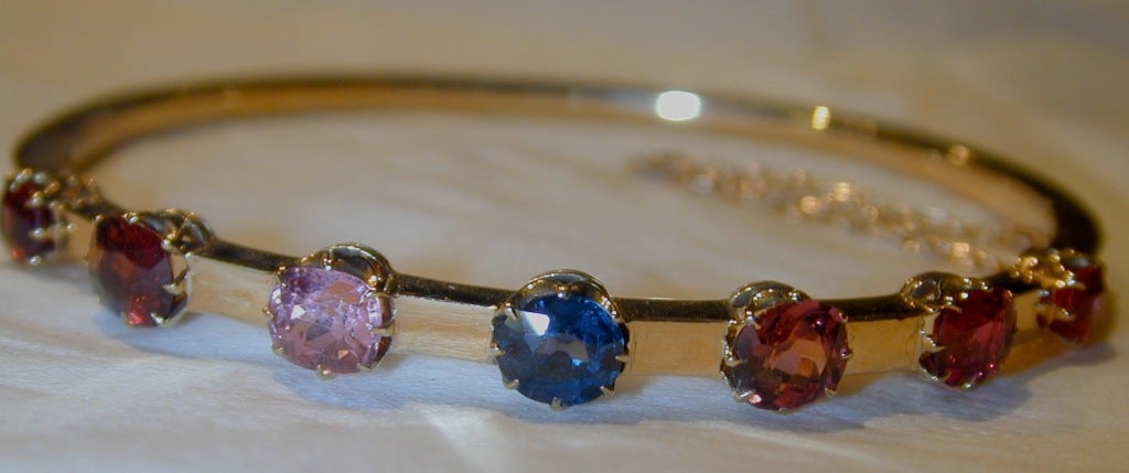 Sparkling with colorful gem stones which include a ruby, a sapphire and pink and red spinels this bangle will glitter on ones wrist and bring color to any outfit. The interior diameter is
2 1/4