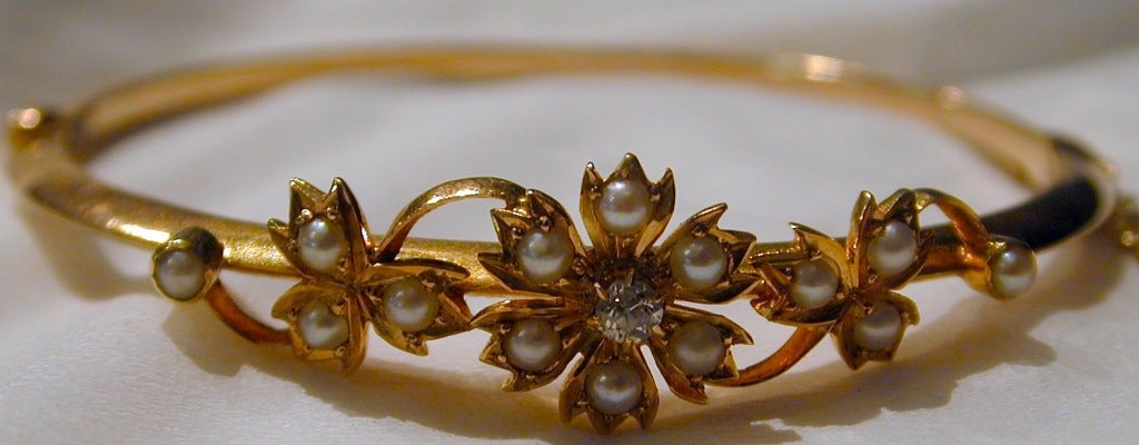 Lovely floral motif bangle bracelet set with natural pearls in 15K gold is attractive worn alone or with other bangles.  The interior diameter is 1 1/4