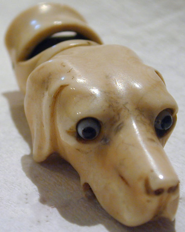 Mit diesem hübschen elfenbeinfarbenen Jagdhund mit Glasaugen als Anhänger an einer langen Kette pfeifen Sie sich durch den Tag. Er misst ungefähr 2