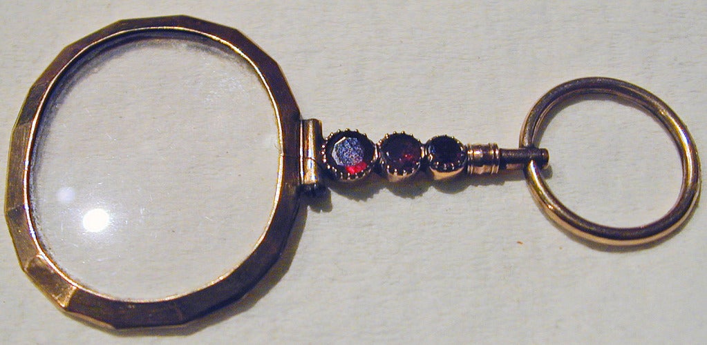 Elegant 9K gold quizzing glass set with almandine garnets. These magnifiers were worn by both men and women in the Georgian period. This piece is unusual in that it is set with gemstones.