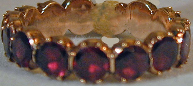 Eternity band of  fifteen almandine garnets set in 15K gold. Wonderful to add to a gold wedding band or stacked with other gem set rings. The ring size is 6 3/4.
