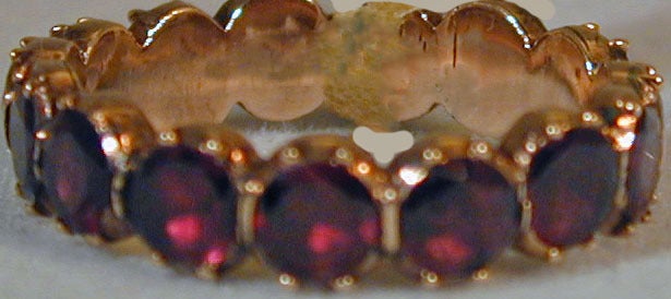Eternity band of  fifteen almandine garnets set in 15K gold. Wonderful to add to a gold wedding band or stacked with other gem set rings. The ring size is 6 3/4.