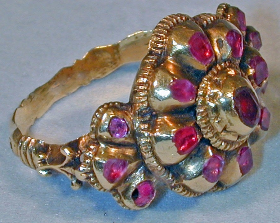 Rubies are set in high carat gold in this large, impressive early Iberian ring. Finely detailed, the central cluster is flanked by a repetition of its floral motif.