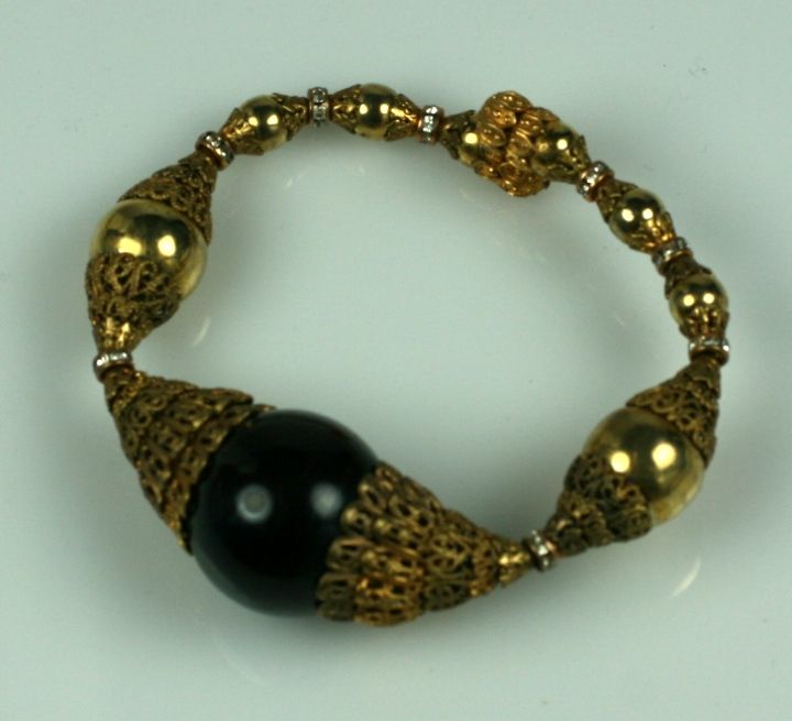 In this Chanel bracelet,the play of layered baroque gilt caps against shiny gilt and black bakelite spheres with pave rondels creates an interesting dynamic. These bracelets are strung on a tension wire and have no closures. They were meant to be