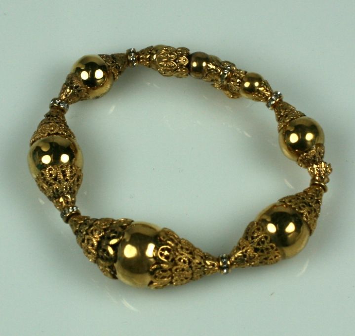 In this Chanel bracelet the play of layered baroque gilt caps against shiny gilt spheres and pave rondels creates an interesting dynamic. These bracelets are strung on a tension wire and have no closures. They were meant to be worn layered as