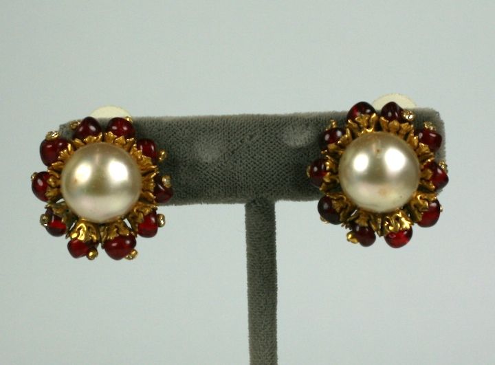 Especially attractive when viewed from the side, these period Chanel earrings combine her love of pearls with the rawness of faux rubies. 

 A row of gilt filigreed caps surrounds the entire large beige center pearl. Within each cup is a hand made