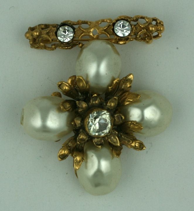 Chanel uses oversized handmade pearls for this pendant brooch of gilded bronze with paste accents by Goossens. The rococo bar brooch has a loop from which the pearl cross can be removed and added onto a necklace. Completely hand made by Atelier