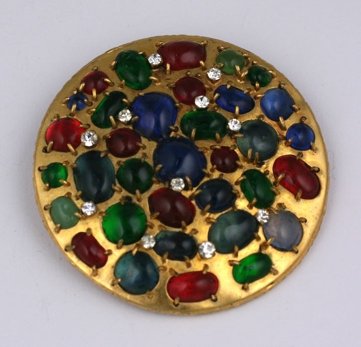 Le barbarisme de Chanel  Broche médiévale ronde composée de cabochons irréguliers en verre coulé sertis de façon irrégulière d'émeraudes, de rubis et de saphirs et de strass en cristal sertis à la broche. Cette broche date de l'époque où les bijoux