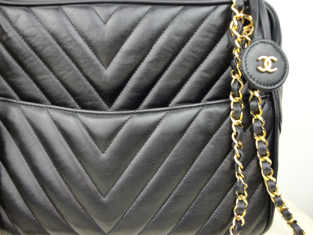 Chanel black leather chevron handbag with chain and leather straps and two exterior pockets. Interior has two zippered pockets and a envelope pocket. Measures 10