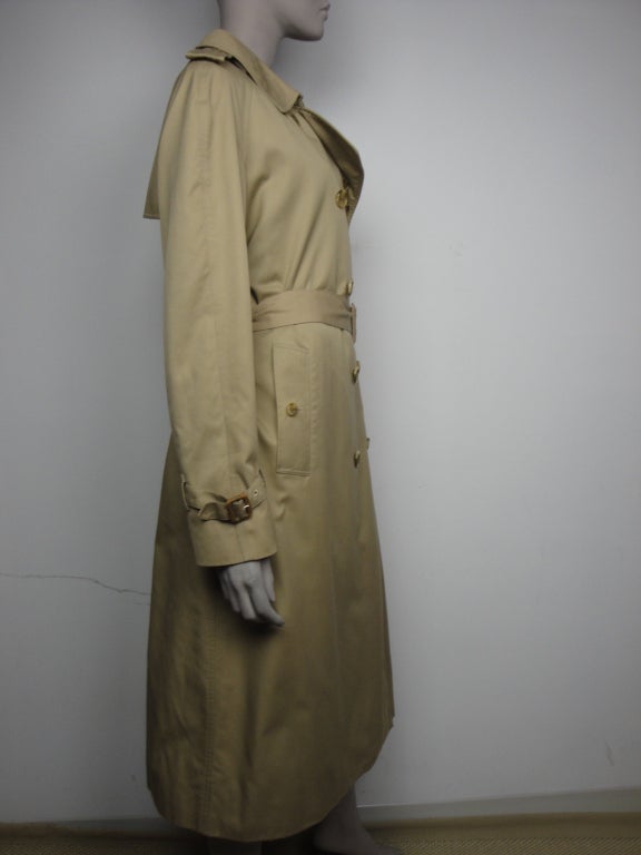 Burberrys classic double breasted trench coat,raglan sleeves with adjustable cuffs,button rear vent, epaulettes and leather buckle belt.
