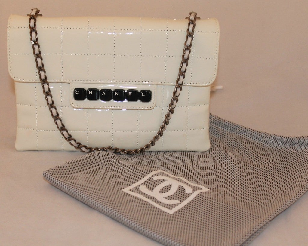Chanel White Patent Leather Quilted Flap Handbag. Block Lettering on Flap, Silver Hardware on chain, 2 compartments inside with 1 zip pocket. Drop handle is 7