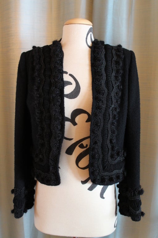 Oscar De La Renta black bolero, wool blend, with pom pom and Embroidered detailing on edge of bolero and around the sleeves. It has light shoulder pads and is in good condition with some minor pilling and general wear on the