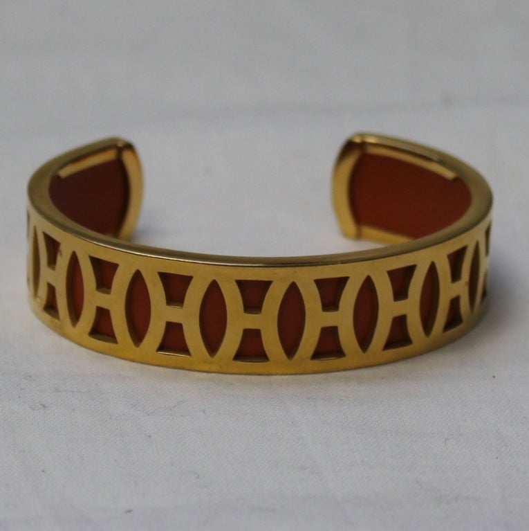 Hermes gold and orange cuff bracelet with H design around it.