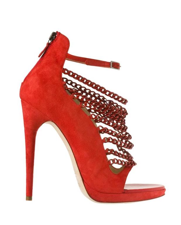 Red suede platform shoes with an open toe by Versus. Red coated chains drape over a large cut-out panel running up the front of the foot. Red suede ankle strap with an adjustable pewter color buckle fastening. A zip fastening runs down the back of