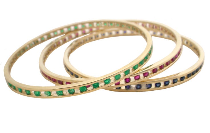 3 actual bangles, each in 18karat yellow gold, 1 set with rubies, 1 set with sapphire and 1 set with emeralds. Each has 48 faceted natural gems, bezel set. They measure 4mm wide and weigh 8.8 Grams and have an inside diameter of 2 5/16
