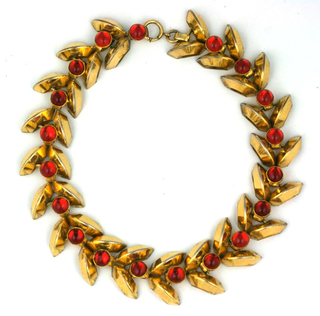 Schiaparelli Haute Couture Retro style necklace from the early 1940s with arc shaped gilt chevrons with ruby glass cabochon centers. These strong architectural motifs emerged in the 1930's and continued until the advent of the war when she came to