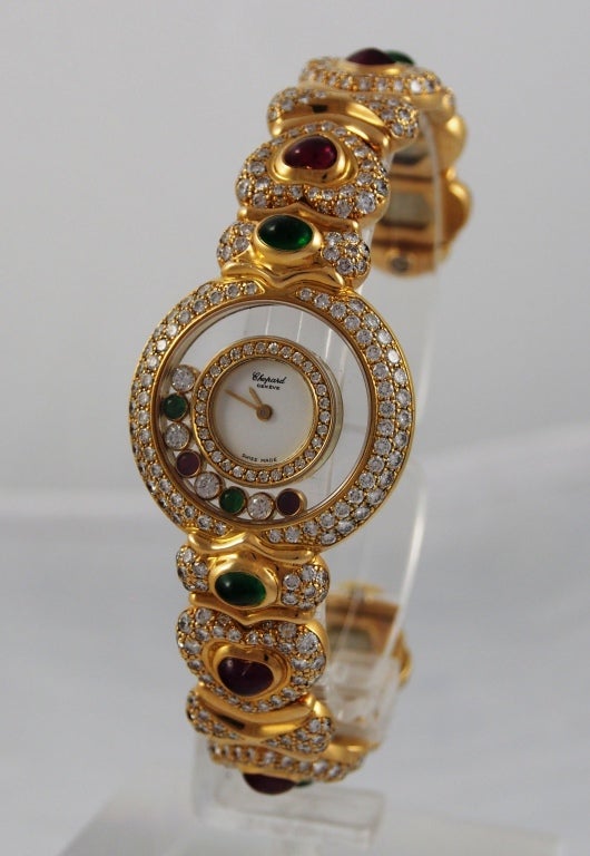 Brand Name: Chopard
Style Number: 20/5769-13
Series: Happy Diamonds
Gender: Lady's
Case Material: 18k Yellow Gold
Dial Color: White with inner set ring of dimaonds and two floating emeralds, two floating rubies, and four floating