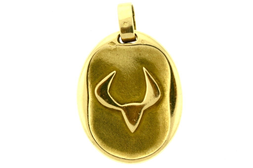 This is a rare and classic 18k zodiac pendant from the 1970s by Cartier Paris. The front depicts the sign of the bull and the back is the Greek symbol for Taurus. Signed Cartier Paris and numbered. French hallmarks present