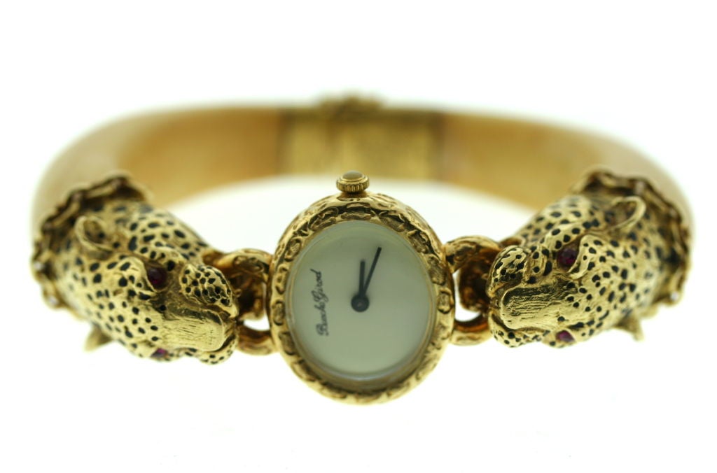 A most interesting hinged bangle bracelet watch from the 1970s by Bueche Girod. Set in 18k gold this confronting leopards watch has an ivory bracelet, inset ruby eyes and black enamel spots. Bueche Girod made bold and stylish jewelry watches in this