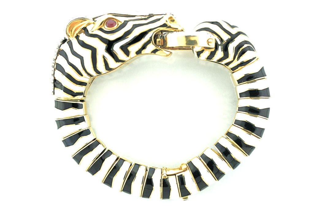 An quintessential and iconic David Webb hinged bracelet of a Zebra motif with black and white stripes of enamel, diamond mane and mouth ring and cabochon ruby eyes. The bold style of this piece is a cornerstone of the <br />
outstanding design of