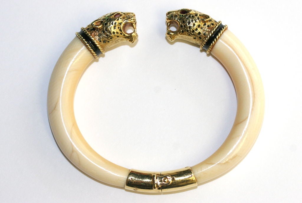 A hinged bangle designed as an ivory bracelet with two confronting 18k gold leopard head terminal ends set with faceted ruby eyes and black enamel collars. Bearing maker's marks for the French jeweler Gay Freres who was known for producing beautiful