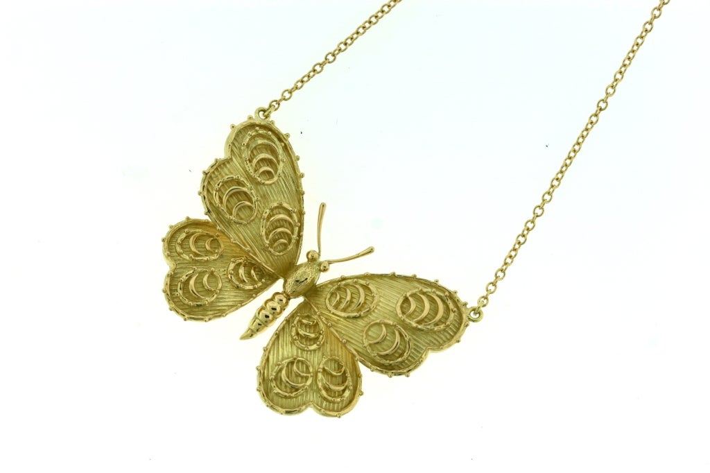 Van Cleef & Arpels 18k gold butterfly pendant with raised wing decorations and texture suspended from 18k gold chain. Wing span on pendant meaures 1.75
