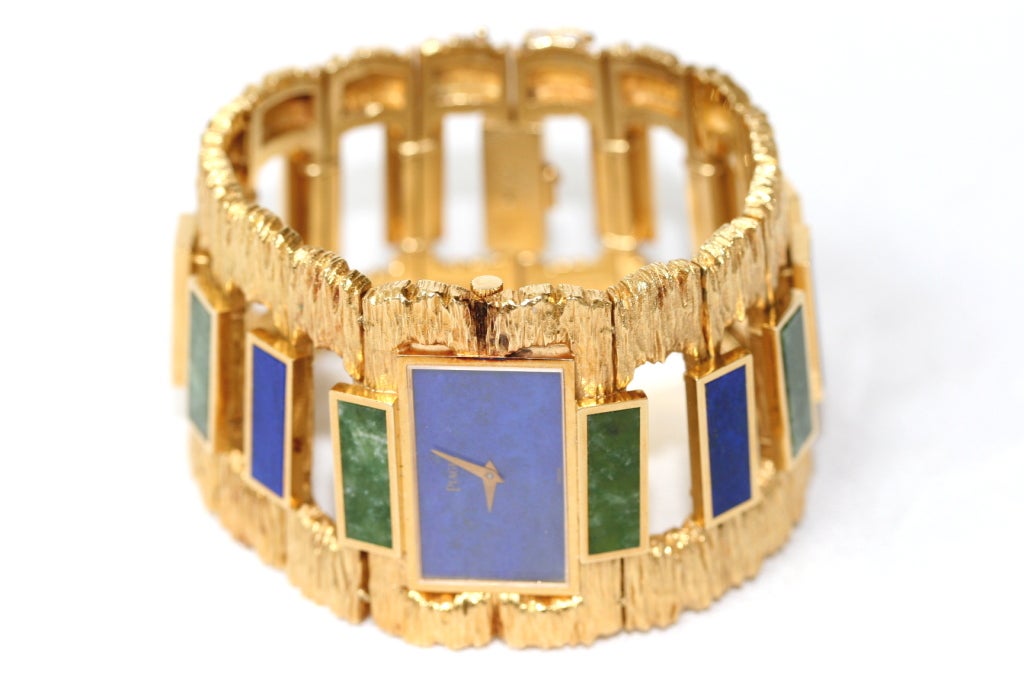 Piaget 18k gold bracelet watch with a lapis face and alternating links of lapis and nephrite jade rectangular cut stones. The goldwork is of a bark-like texture speaking to the organic motifs of the 1970s. 

This was a superb time for Piaget and
