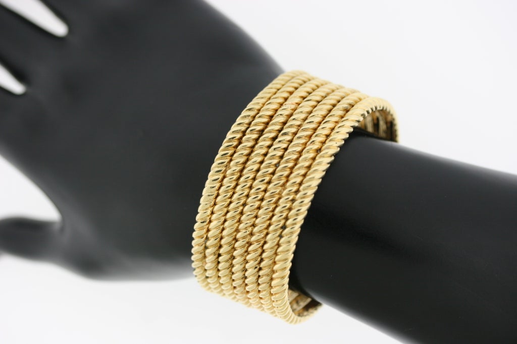 Van Cleef & Arpels 18k gold twisted ropework cuff bracelet. Opening in back allows bracelet to slip on over wrist and is adjustable. This is a very tailored and elegant bracelet which can be worn on its own or paired wth other bangles for a more