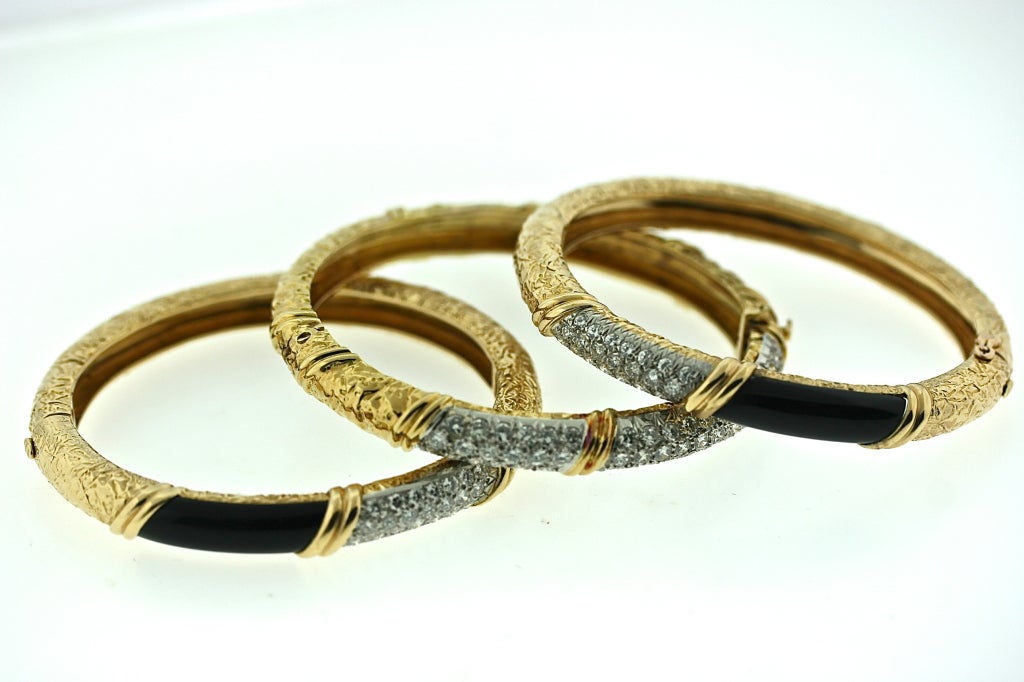 Van Cleef & Arpels set of three 18k textured gold hinged bangle bracelets. Two of the bracelets are designed with two top sections of diamonds set in platinum and black onyx. The two top sections of the third bracelet are both set in diamonds and