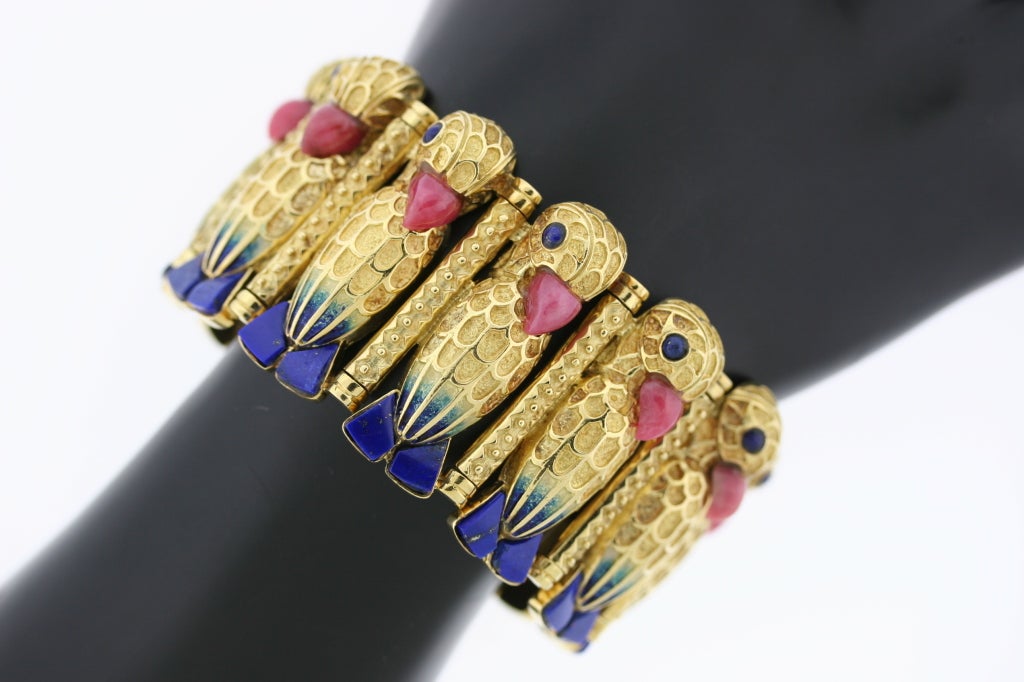A spectacular 18k gold bracelet designed as a succession of 10 parrot motif links with lapis feet and eyes, rhodochrosite beaks and ombre enamel bodies. The workmanship and detail of execution is precise as each piece of lapis and rhosochrosite are