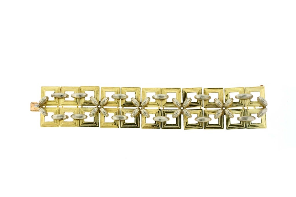 Square platforms of 18k yellow and white gold  are laced together by rounded ribbed links in alternating X and dash patterns. A classic and bold look from the 1970s by master French jeweler Andre Vassort. Signed with maker's mark for Andre Vassort.