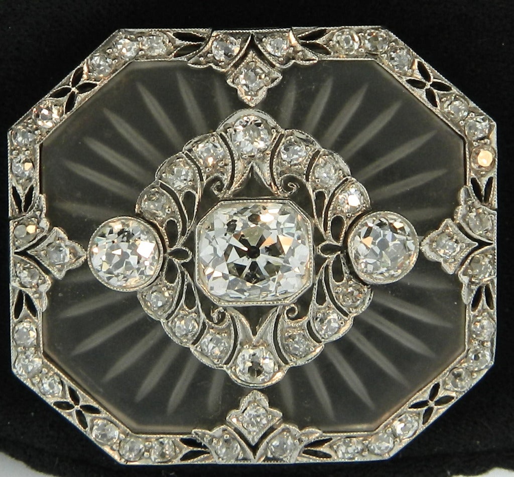 An amazing Art Deco Pendant/Brooch, featuring a carved frosted rock-crystal panel within an octagonal platinum and diamond frame, centering upon a stunning 2.30ct estimated old European cushion brilliant cut diamond.