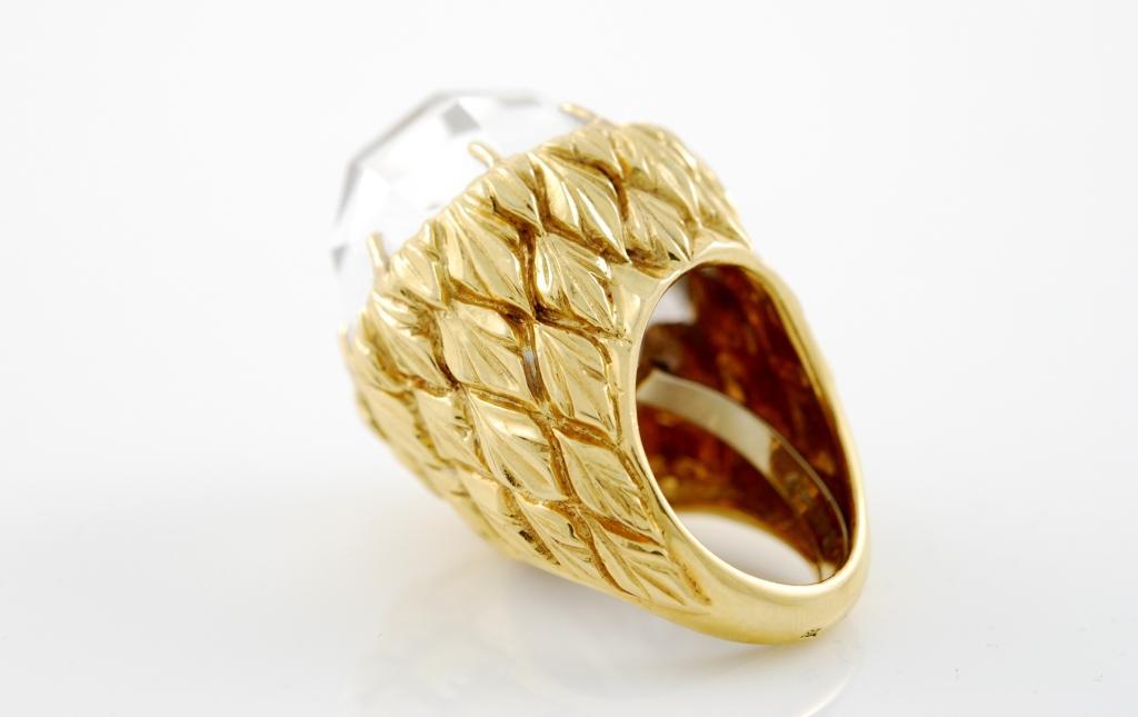 18kt yellow gold and rock crystal dome ring . The base is in hammered gold forming geometric designs and the top is made of faceted rock crystal.